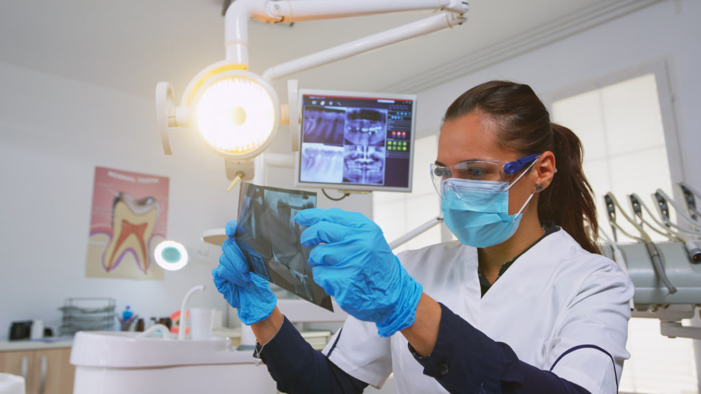 Dentist looking at teeth x-rays of patient dental emergency.