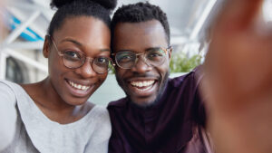 African American couple taking a selfie and smiling because they know they'll have good oral health over 40.