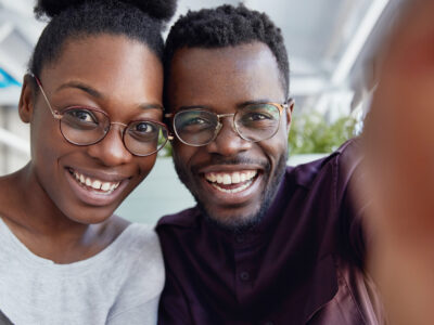 African American couple taking a selfie and smiling because they know they'll have good oral health over 40.