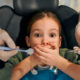 Little girl covering her mouth in the dental chair while trying to overcome dental anxiety.