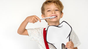 Kid brushing his teeth wondering how often to get a dental cleaning.
