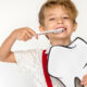 Kid brushing his teeth wondering how often to get a dental cleaning.