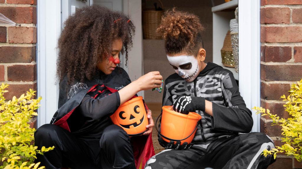 Two kids looking through Halloween candy and thinking about Halloween dental safety.