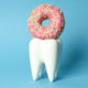 Does sugar really hurt your teeth? Image of a tooth with a pink donut on top of it.