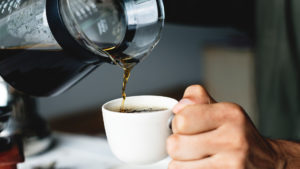 Is drinking coffee bad for your teeth? Closeup image of someone pouring coffee into a mug.