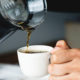 Is drinking coffee bad for your teeth? Closeup image of someone pouring coffee into a mug.