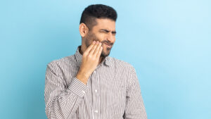 Man holding his cheek wondering if he has a dental abscess.