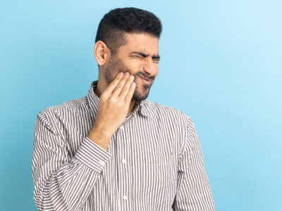 Man holding his cheek wondering if he has a dental abscess.