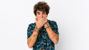 Photo of young man with his hands covering his mouth thinking about dangerous TikTok dental hacks